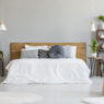 Patterned armchair in grey bedroom interior with poster on table with plants next to bed. Real photo